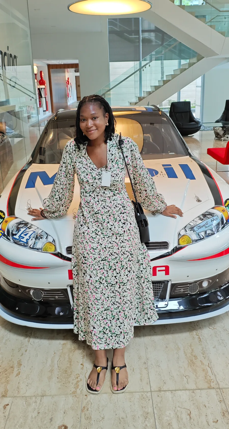 Timi Adepegba in front of a Mobil racing car at the ExxonMobil campus in Texas
